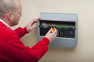 Fire alarm service technician servicing fire alarm panel with the cover open